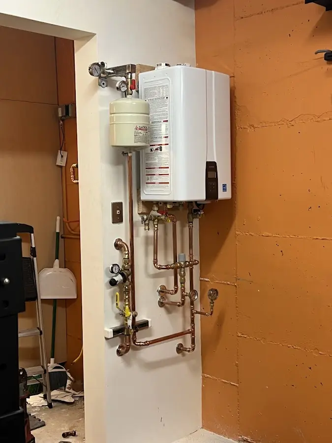 Plumbing technician inspecting water heater connections in Falls City